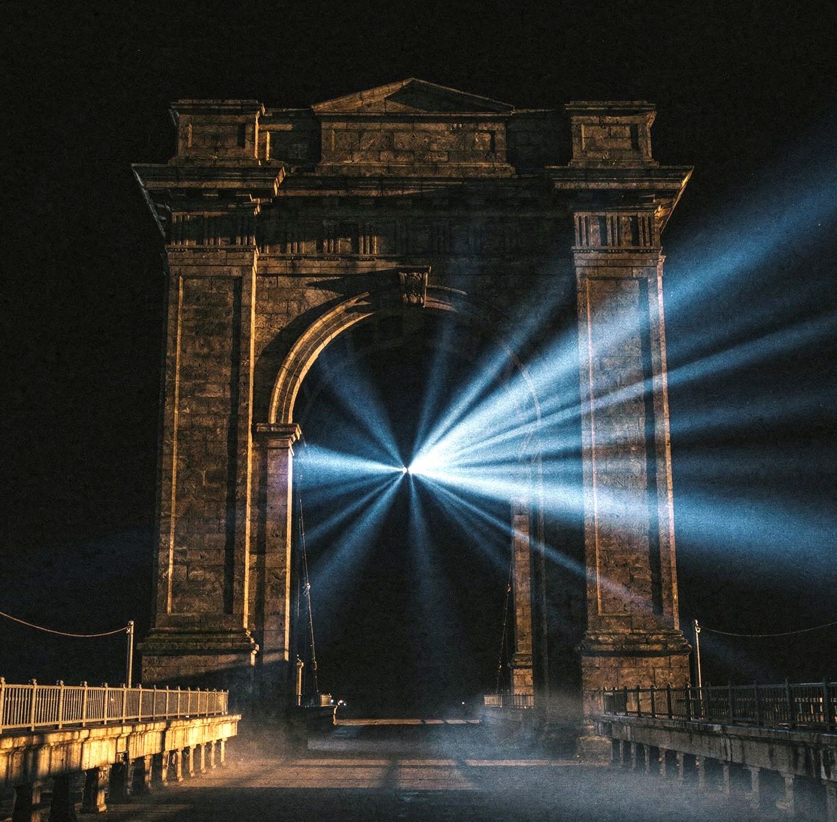 An illuminated stone arch projecting beams of light into the night.